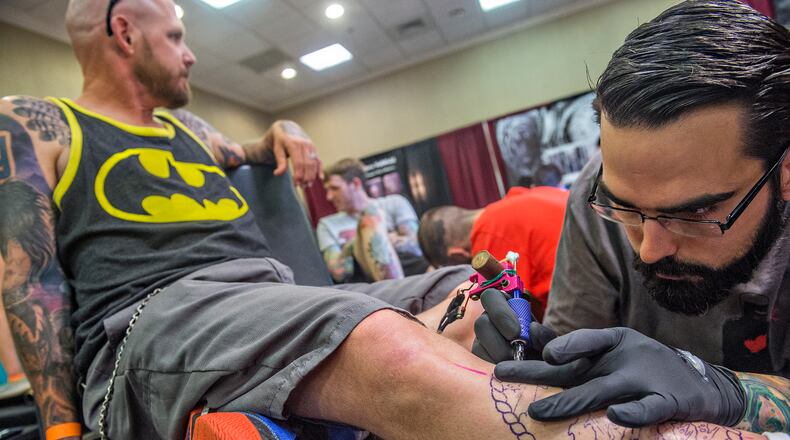 June 20, 2015 Atlanta - Matt Brumelow (right) works on a leg tattoo for Neil Guida during the 19th annual Atlanta Tattoo Expo at the Wyndham Atlanta Galleria hotel on Saturday, June 20, 2015. Around 100 tattoo artists from across the country were booked solid throughout the three day event as hundreds of people came out to watch and get tattooed. JONATHAN PHILLIPS / SPECIAL