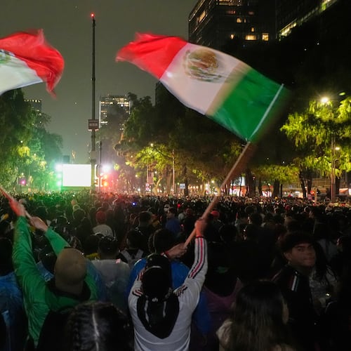 Mexican fans wave flags as they watch the World Cup round of 32 soccer match between Mexico and Ecuador near the Angel of Independence monument in Mexico City, Tuesday, June 30, 2026. (AP Photo/Marco Ugarte)