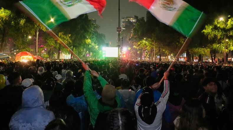 Mexican fans wave flags as they watch the World Cup round of 32 soccer match between Mexico and Ecuador near the Angel of Independence monument in Mexico City, Tuesday, June 30, 2026. (AP Photo/Marco Ugarte)