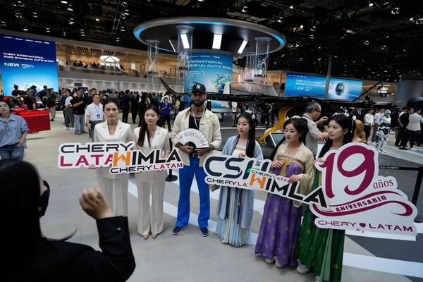 Visitors holding up signs celebrating the 19th year of Chery's presence in Latin America during the Shanghai auto show on Wednesday, April 23, 2025. (AP Photo/Ng Han Guan)