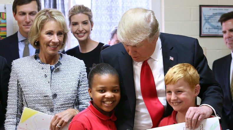 President Donald Trump thanks fourth-graders Janayah Chatelier and Landon Fritz for the homemade greeting cards they presented during his visit to St. Andrew Catholic School in Orlando, Fla., Friday, March 3, 2017. With the president, from left to right, are: Trump son-in-law Jared Kushner; U.S. Secretary of Education Betsy DeVos, and Trump daughter Ivanka Trump. (Joe Burbank/Orlando Sentinel via AP)
