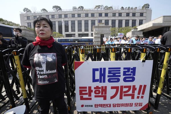 A member of ruling People Power Party stands against impeachment of impeached South Korean President Yoon Suk Yeol in front of the Constitutional Court in Seoul, South Korea, Tuesday, April 1, 2025. The banner reads "Dismiss impeachment." (AP Photo/Ahn Young-joon)