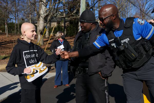 Bowie greets Sandy Springs Police officer Jarrell Greene (center) and Special Operations Bike Unit officer Will Smith (right) during a sendoff by the College Football Playoff and Dream On 3 in Atlanta. (Jason Getz/AJC)