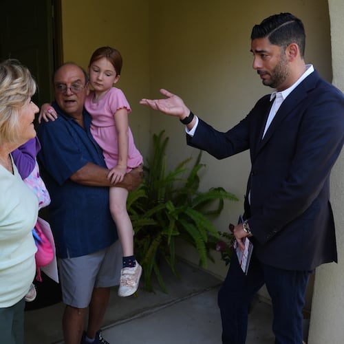 Ammar Campa-Najjar, right, a Democratic candidate for California's 48th Congressional District, speaks with a family as he canvasses in a neighborhood Saturday, May 23, 2026, in San Marcos, Calif. (AP Photo/Gregory Bull)