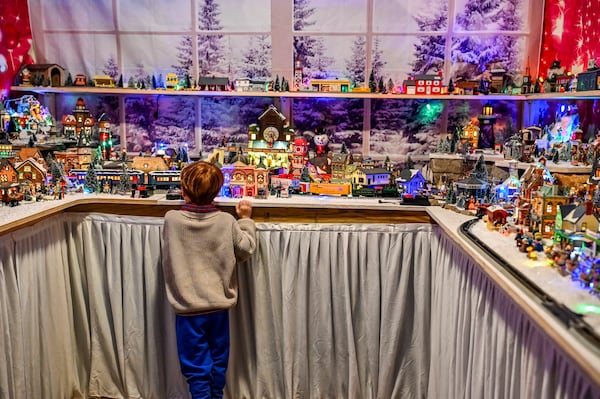 A young Savannah neighbor gets a closer look at the extensive Christmas-themed model train display housed in Don Mathis' garage. (Sarah Peacock for the AJC)