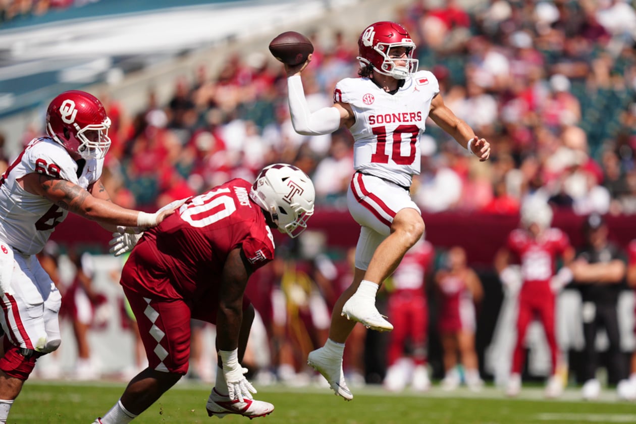 Oklahoma quarterback John Mateer (right) — pictured leaping as he throws the ball against Temple in September — was an early Heisman Trophy candidate in 2025 before his season was derailed by thumb surgery. (Derik Hamilton/AP)