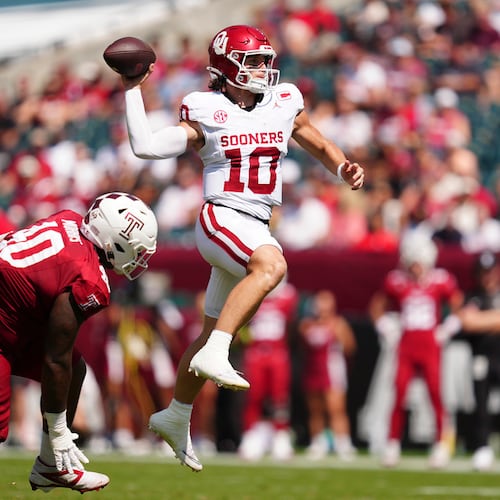 Oklahoma quarterback John Mateer (right) — pictured leaping as he throws the ball against Temple in September — was an early Heisman Trophy candidate in 2025 before his season was derailed by thumb surgery. (Derik Hamilton/AP)