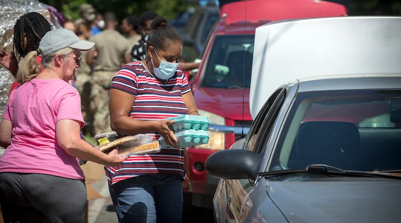 Volunteers with the Summertown Food Pantry place food into the back seat of a car. The head of the Atlanta Community Food Bank said that this summer, people have sought 50% more food from his organization’s pantries than last year. The use of food stamp benefits has also surged, adding nearly 250,000 households in Georgia in the past year. (AJC Photo/Stephen B. Morton)