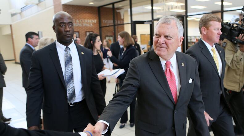 Gov. Nathan Deal shakes hands as he departs a high school with chief aide Chris Riley at his side. BOB ANDRES / BANDRES@AJC.COM