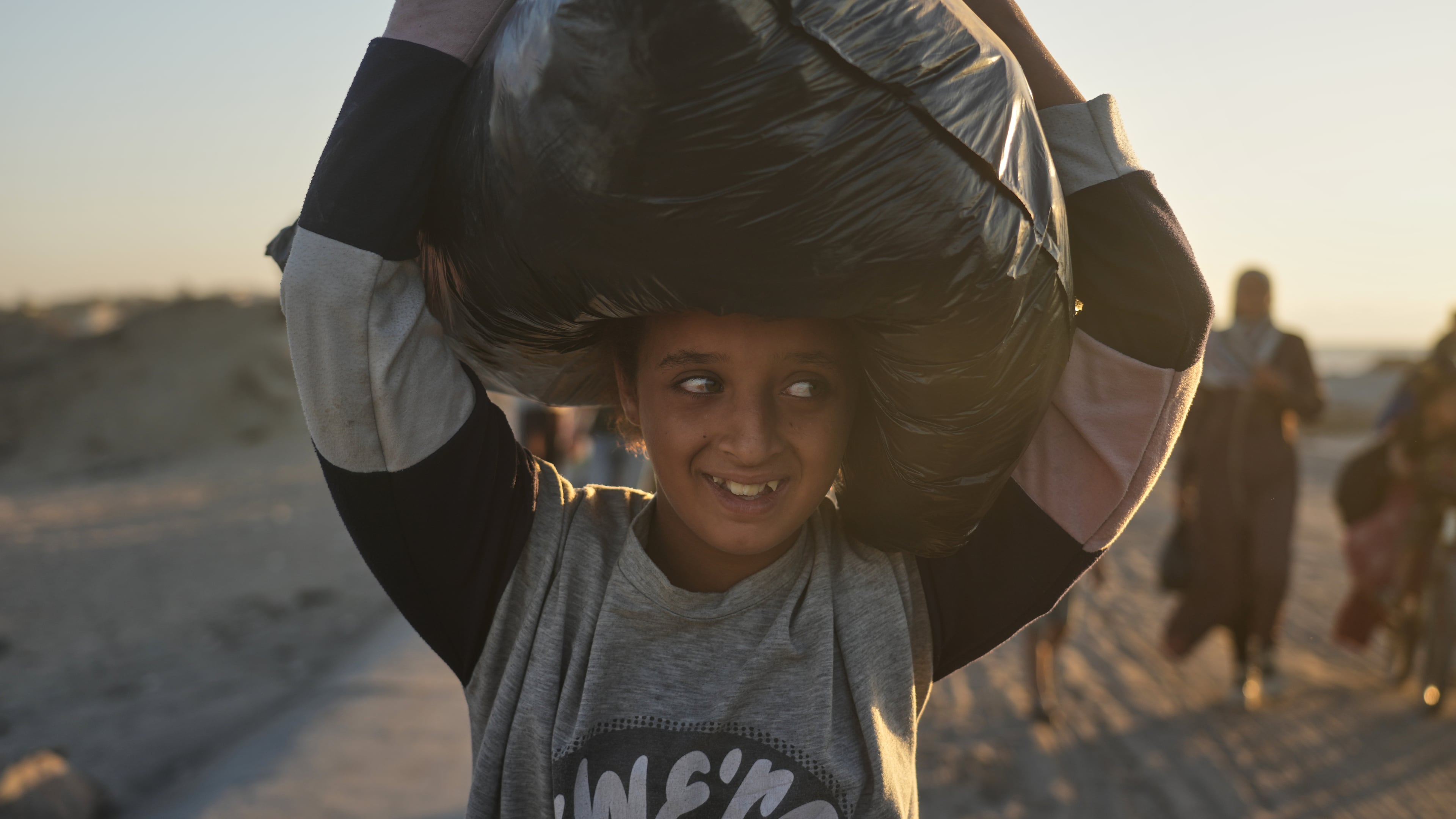 A displaced Palestinian girl carries a bag on her head as she walks along the coastal road near Wadi Gaza in the central Gaza Strip, heading toward Gaza City, Friday, Oct. 10, 2025, after Israel and Hamas agreed to a pause in their war and the release of the remaining hostages. (AP Photo/Abdel Kareem Hana)