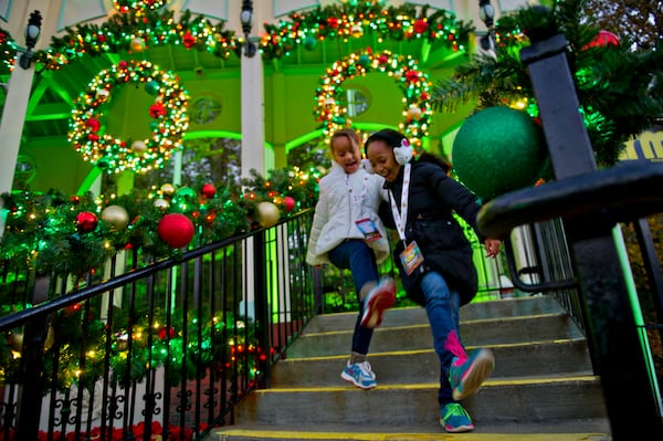Madelyn Williams (right) and Tamia Draper danced their way down a set of steps inside Six Flags Over Georgia in Austell on Friday, Nov. 21, 2014. The park was decorated in 10 sections of holiday lights for the first time since 1990. (Jonathan Phillips/Special)