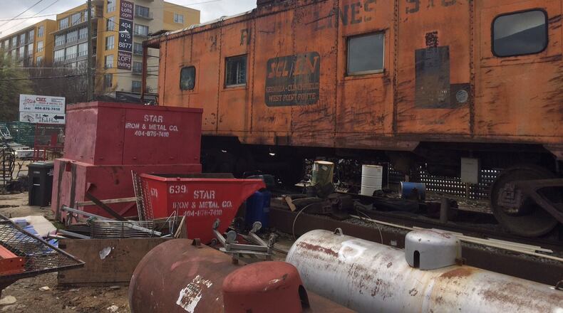 The caboose at Star Iron and Metal will stay, but all the junk is going as the property may very well end up looking like the apartment complex looming in the background. Bill Torpy / btorpy@ajc.com