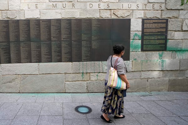 A woman looks at Paris' Shoah Memorial defaced with green paint after several Jewish sites across the capital were defaced with green paint. Saturday, May 31, 2025 in Paris. (AP Photo/Aurelien Morissard)