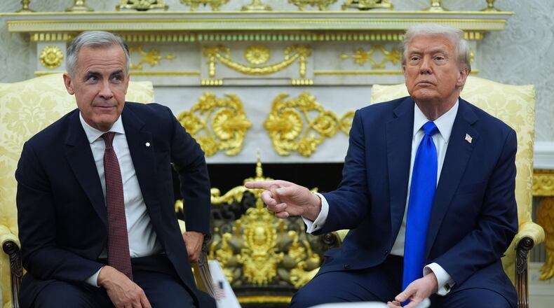 FILE - President Donald Trump gestures alongside Canadian Prime Minister Mark Carney as they meet in the Oval Office of the White House, Oct. 7, 2025, in Washington. (AP Photo/Evan Vucci, File)