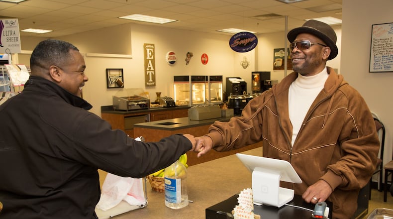 Anthony Brewer (left) fist pumps Eddie Mial, who runs a snack shop in the basement of the DeKalb County Courthouse in Decatur. The gregarious Mial greets every customer who comes in the store. (Photo by Phil Skinner)