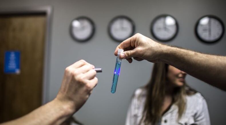 One player holds an object as another player shines a light looking for clues at Urban Escape Games. CONTRIBUTED BY: BRANDEN CAMP