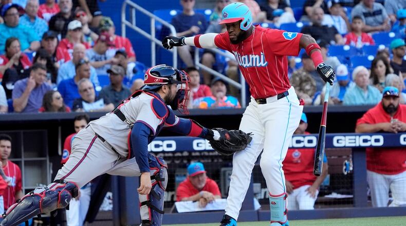Atlanta Braves catcher Travis d'Arnaud, left, tags Miami Marlins' Bryan De La Cruz after De La Cruz struck out swinging during the third inning of a baseball game, Saturday, April 13, 2024, in Miami. (AP Photo/Wilfredo Lee)