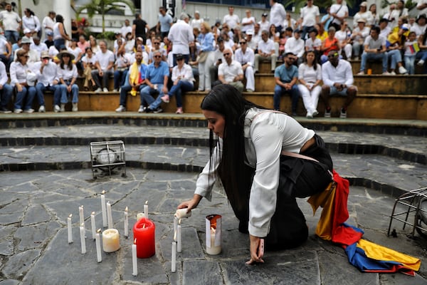 A woman lights a candle at a gathering to pray for Colombian Senator Miguel Uribe Turbay's recovery after he was shot at a political rally, in Cali, Colombia, Sunday, June 8, 2025. (AP Photo/Santiago Saldarriaga)