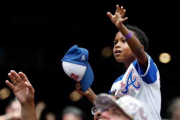A young Braves fan waves for a ball during the ninth inning of Sunday's game.