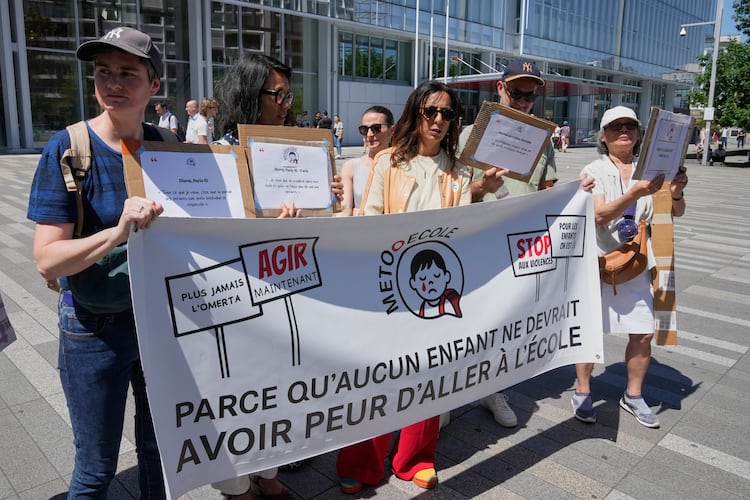 Members and supporters of the #METooEcole (#METooSchool) movement stage a protest to draw attention to a child abuse scandal in France in front of the courthouse in Paris on Tuesday May 26, 2026. The banner reads, in French, "Because no child should ever be afraid to go to school." (AP Photo/Michel Euler)
