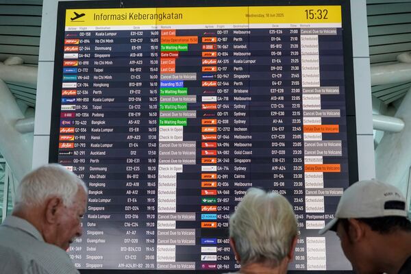 Passengers check an information board showing disrupted flight schedule due to the eruption of Mount Lewotobi Laki-Laki, at Ngurah Rai International Airport in Badung, Bali, Indonesia, Wednesday, June 18, 2025. (AP Photo/Herdyanto)