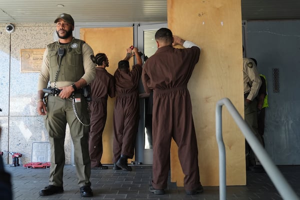 Inmates board up the U.S. Department of Justice Federal Bureau of Prisons during a protest on Friday, June 6, 2025, in Los Angeles. (AP Photo/Jae C. Hong)