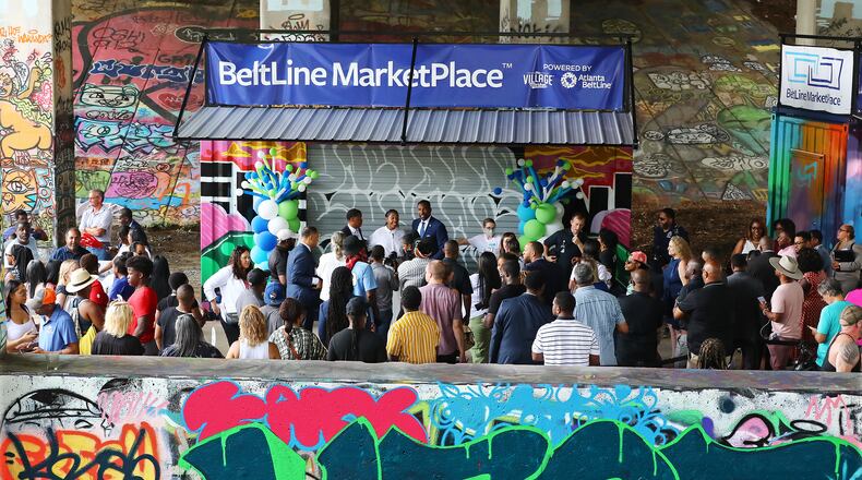 A crowd including Atlanta Mayor Andre Dickens, Atlanta Beltline President and CEO Clyde Higgs and The Village Market's Founder & CEO Dr. Lakeysha Hallmon (at center) gather for a ribbon-cutting ceremony for the inaugural Beltline Marketplace under the Freedom Parkway Bridge, on Wednesday, July 13, 2022. (Curtis Compton / Curtis Compton@ajc.com)