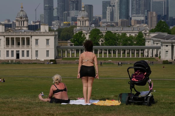 People sunbathe on a sunny day at a park in London, Thursday, May 1, 2025. (AP Photo/Kin Cheung)