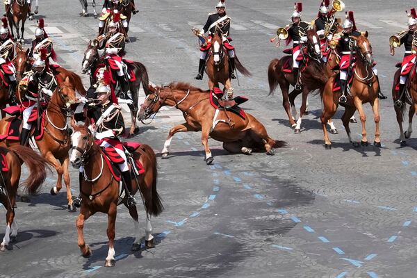A horse slides on the pavement during the Bastille Day parade, Monday, July 14, 2025 in Paris. (AP Photo/Christophe Ena)