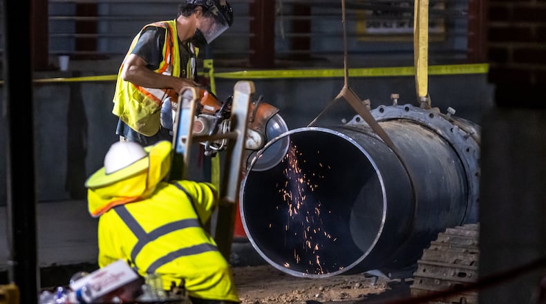 A large 30-inch pipe was seen being lowered into the hole at 11th and West Peachtree Street Tuesday morning, June 4, 2024. According to the city, the Department of Watershed Management was ready to start installing and conducting the remaining steps to restore water service. (John Spink/AJC)