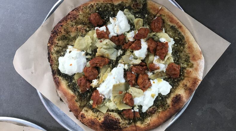 This build-your-own pizza from Your Pie includes basil pesto, ricotta, Italian sausage, artichoke hearts and garlic on a wheat crust. LIGAYA FIGUERAS / LFIGUERAS@AJC.COM