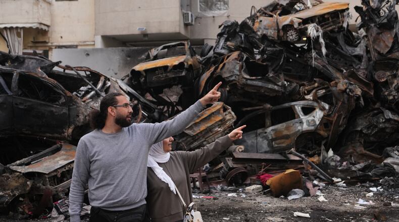 Residents gesture and point toward damage as they stand near charred cars at the site of a building destroyed in an Israeli airstrike last Wednesday in central Beirut, Lebanon, Tuesday, April 14, 2026. (AP Photo/Hassan Ammar)