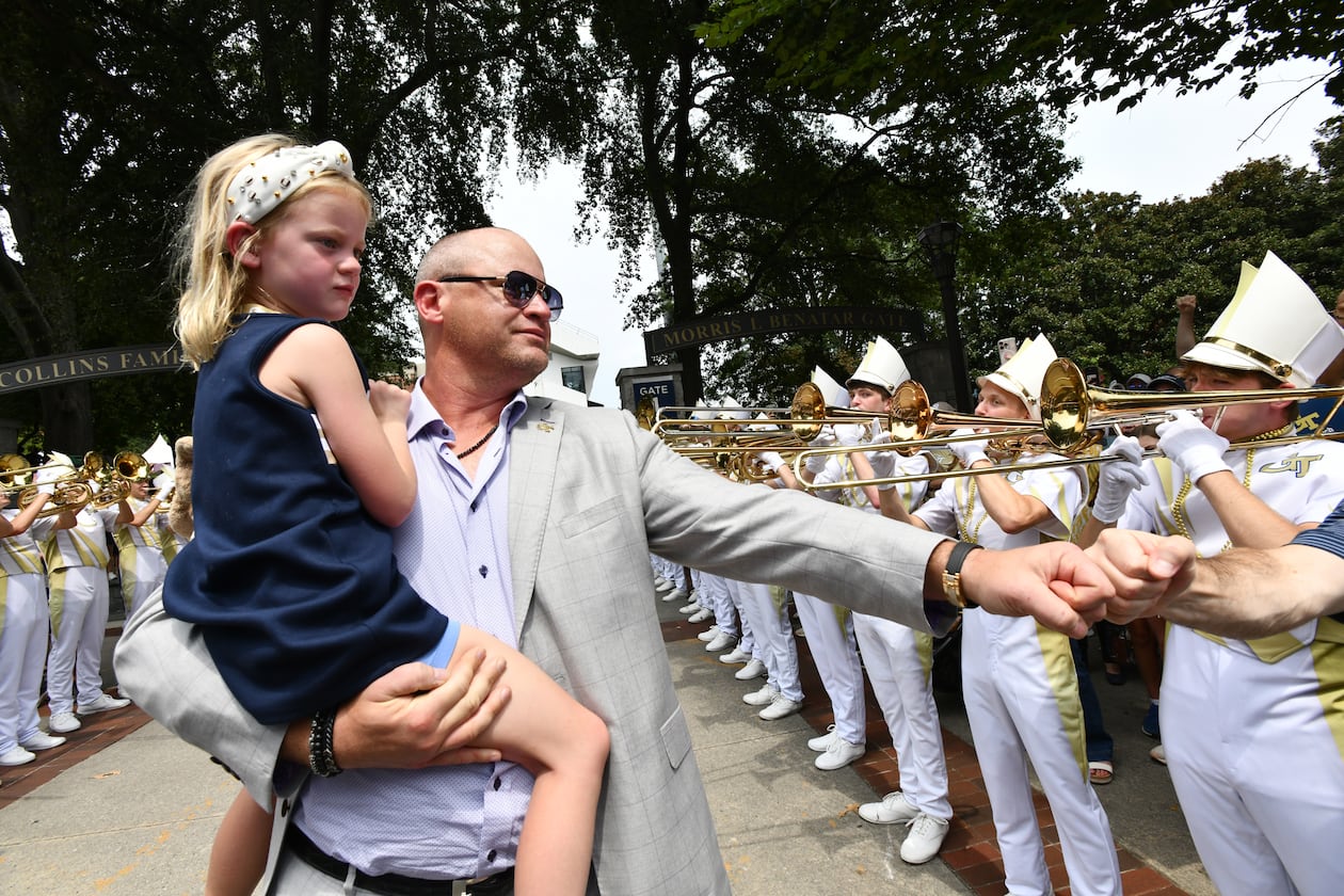 Georgia Tech coach Brent Key and his daughter, Harper, arrive with players and coaches before the home opener Sept. 6, 2025, against Gardner-Webb at Bobby Dodd Stadium in Atlanta. (Hyosub Shin/AJC)