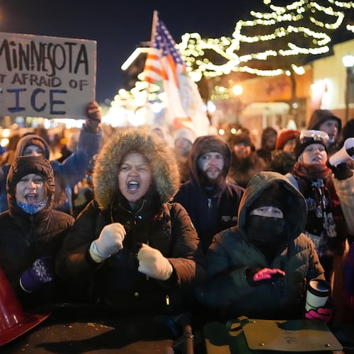 Protesters chant and bang on trash cans as they stand behind a makeshift barricade during a protest in response to the death of 37-year-old Alex Pretti, who was fatally shot by a U.S. Border Patrol officer earlier in the day, Saturday, Jan. 24, 2026, in Minneapolis. (AP Photo/Adam Gray)