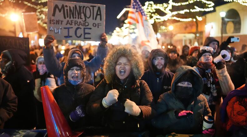 Protesters chant and bang on trash cans as they stand behind a makeshift barricade during a protest in response to the death of 37-year-old Alex Pretti, who was fatally shot by a U.S. Border Patrol officer earlier in the day, Saturday, Jan. 24, 2026, in Minneapolis. (AP Photo/Adam Gray)