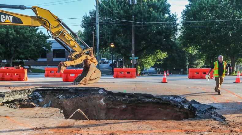 June 28, 2023 Atlanta: One day after a massive sinkhole opened along one of the most traveled roads in Midtown Atlanta, swallowing an SUV, traffic was moving again on Wednesday, June 28, 2023. Crews were still digging out dirt and temporary roadblocks remain in place on Ponce de Leon Avenue, but at least one eastbound lane and two westbound lanes are open. The portion of road between Myrtle Street and Argonne Avenue had been closed to traffic since Tuesday afternoon to repair a broken sewer pipe that caused the surface to collapse. Officials with the city’s department of watershed management described the culprit as a “breach” in the pipe about 15 to 18 feet below the surface but did not elaborate further. Crews worked at the site overnight excavating the hole and making the repairs. A spokesperson for the department said there is no estimated time of completion. Atlanta police said they received a call just before 2:15 p.m. Tuesday about the vehicle that fell into a hole at 265 Ponce de Leon Avenue, in front of Torched Hop Brewery and across the street from Mary Mac’s Tea Room. The area is located just east of Piedmont Avenue. Photos showed the front of the white Ford Expedition tilted diagonally inside the sinkhole, with only its rear tires still on a level surface. According to Channel 2 Action News, the driver was trying to make a right turn when the vehicle fell in. He managed to climb out of the driver’s-side window, while his wife escaped out of a back door. (John Spink / John.Spink@ajc.com)