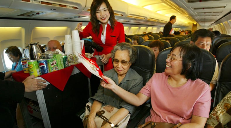 A flight stewardess is seen serving drinks and snacks on board the Air Asia Boeing 737-300 flight from Bangkok to Phuket on February 25, 2004 in Bangkok, Thailand. (Paula Bronstein/Getty Images)