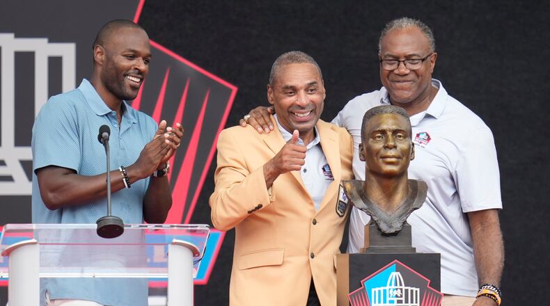 Former NFL player Roger Craig, center, unveils his bust with son, Roderick Craig, left, and Jamie Williams during the Pro Football Hall of Fame induction ceremony at the Pro Football Hall of Fame, in Canton, Ohio, Saturday, Aug. 8, 2026. (AP Photo/Sue Ogrocki)