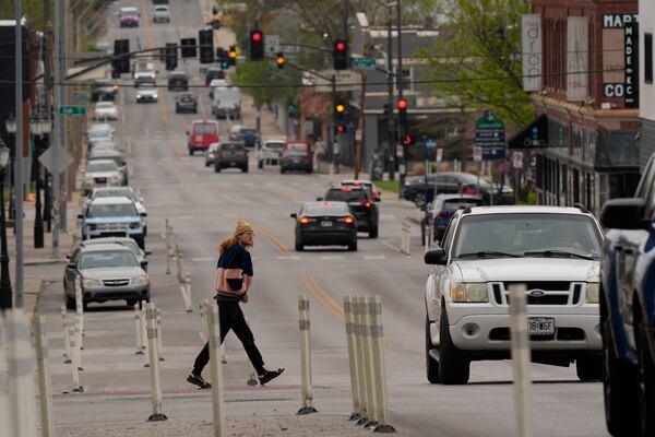 A man crosses 31st Street in Kansas City, Mo., where the city implemented a "road diet" reducing the street from four lanes to two in an effort to reduce speeding and accidents, Thursday, April 17, 2025. (AP Photo/Charlie Riedel)