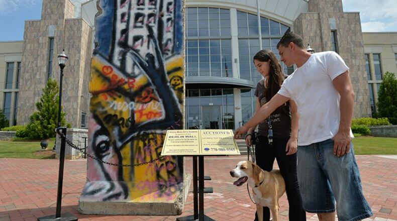 Dianne Meuse and her friend, Adam Pietroski, both of Buford, check out a 12-foot-tall section of the Berlin Wall on display in front of Suwanee City Hall. AJC File