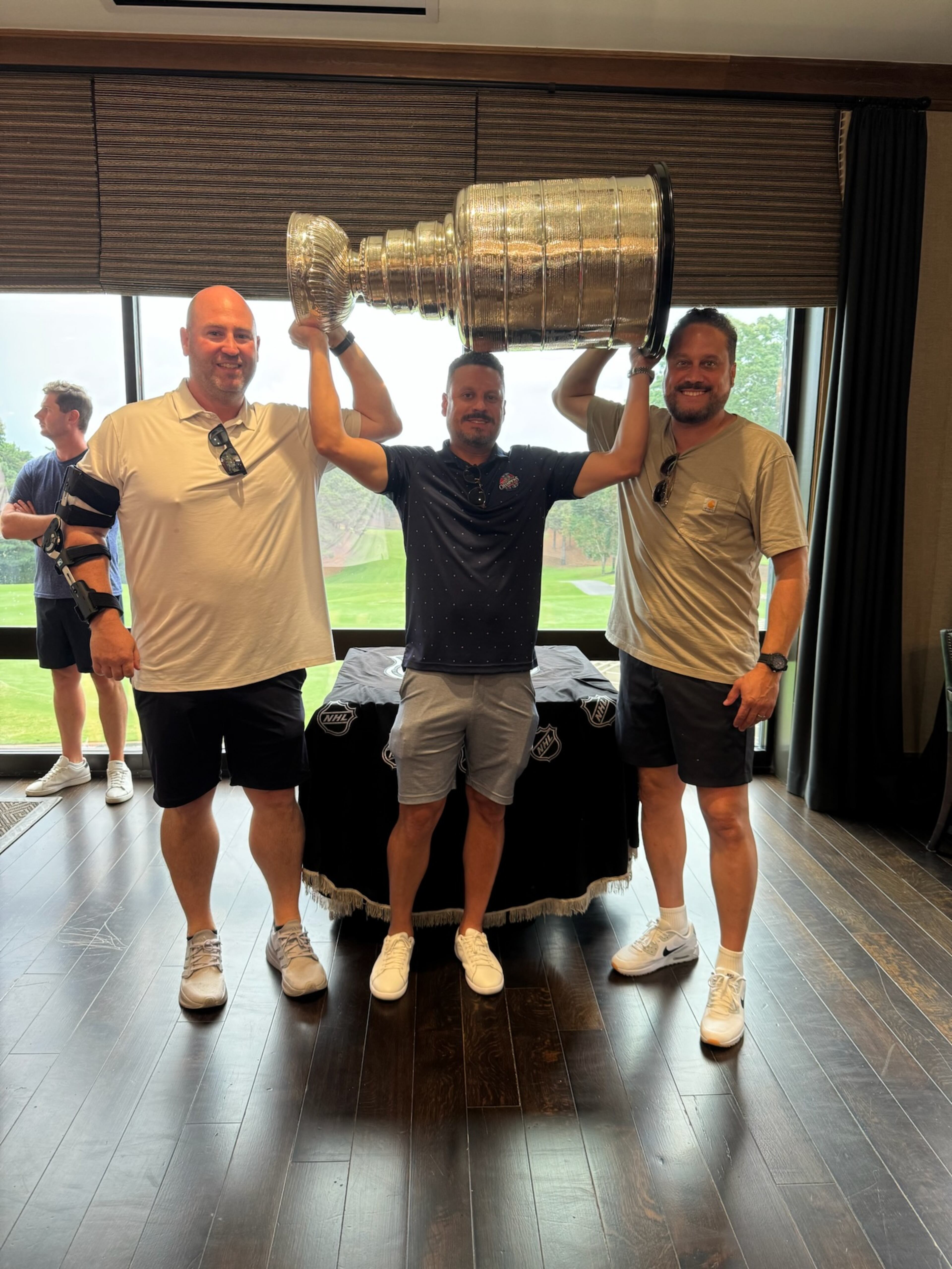 Former Kennesaw State assistant football coach Liam Klein (left) helps hold up the Stanley Cup with friend and former co-worker Mike Huff at the St. Regis Atlanta hotel July 15, 2025. On the right is Huff’s brother Eli. By tradition, only people whose names are inscribed on the cup (as Huff’s is) are allowed to hoist the cup. (Courtesy of Liam Klein)