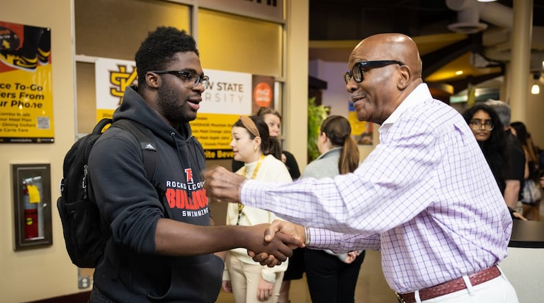 James Hughes shakes hands with a student at his retirement celebration at a Kennesaw State University dining hall on Dec. 7.