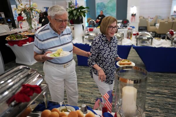 A resident assists her partner to navigate an Independence Day buffet in the independent living facility at the Toby and Leon Cooperman Sinai Residences, July 4, 2025, in Boca Raton, Fla. (AP Photo/Rebecca Blackwell)