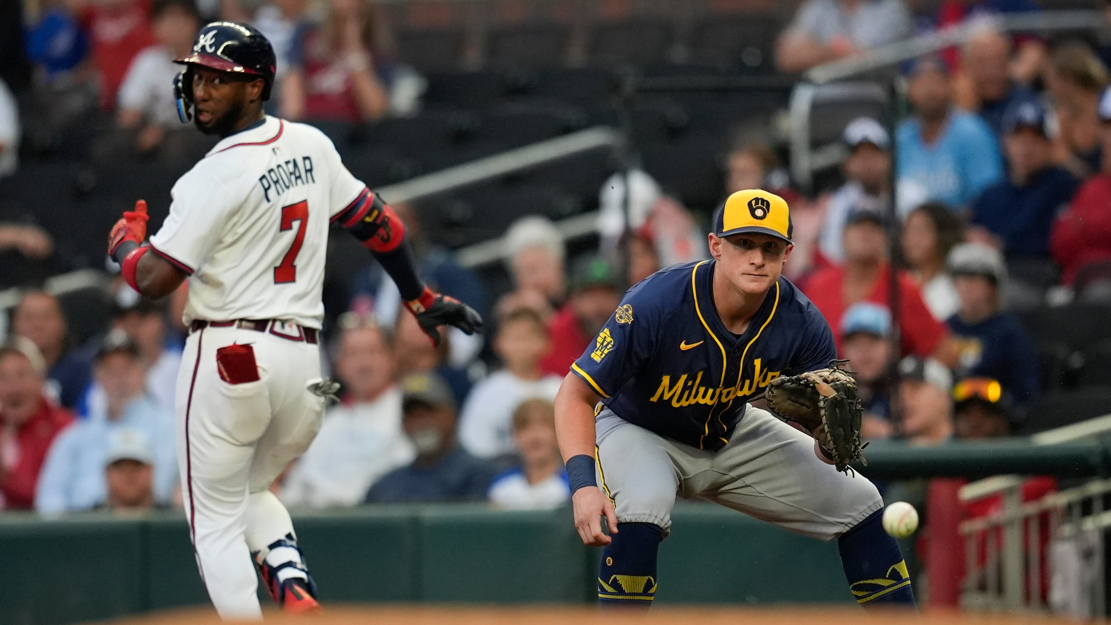 Milwaukee Brewers first baseman Andrew Vaughn (28) waits for the ball as Atlanta Braves' Jurickson Profar (7) is safe in the first inning of a baseball game, Tuesday, Aug. 5, 2025, in Atlanta. (AP Photo/Mike Stewart)