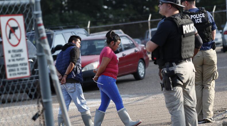 Two people are taken into custody at a Koch Foods Inc. plant in Morton, Miss., on Wednesday, Aug. 7, 2019. U.S. immigration officials raided several Mississippi food processing plants on Wednesday and signaled that the early-morning strikes were part of a large-scale operation targeting owners as well as employees. (AP Photo/Rogelio V. Solis)