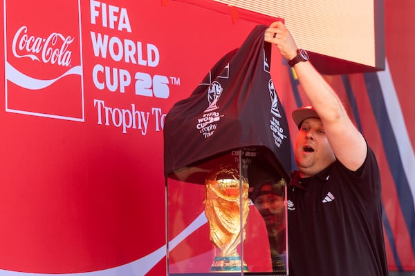 A worker unveils the 2026 FIFA World Cup trophy at The Battery at Truist Park in Atlanta on May 14, 2026. (Arvin Temkar/AJC)