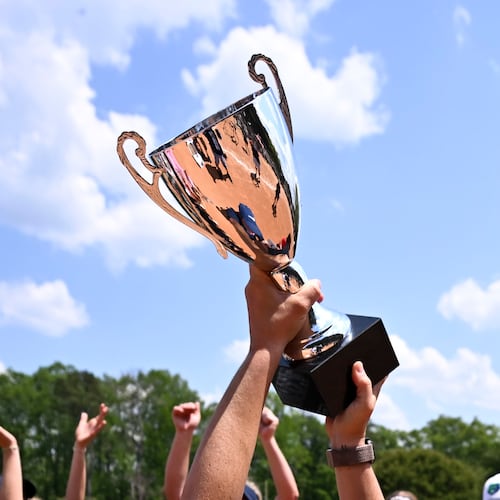 Creekview head coach Jennifer Maloney holds her GHSA championship trophy high Thursday, April 23, 2026, after beating Cherokee in a slow pitch softball game at Twin Creeks Softball Complex. (Daniel Varnado for the AJC)