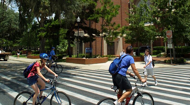 FILE - University of Florida students make their way through a crosswalk near the campus landmark Century Tower in Gainesville Fla. (AP Photo/Rob C. Witzel, file)