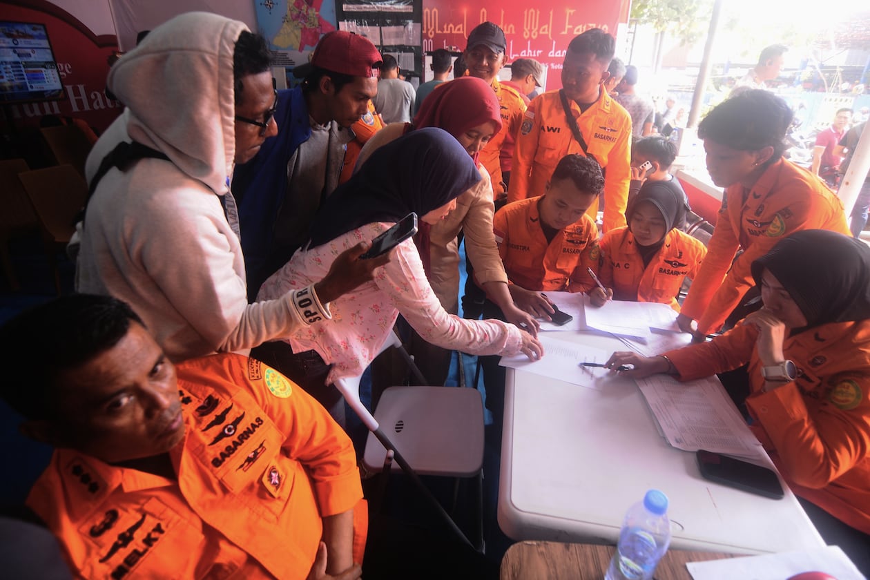 People look for the names of their family members on a passenger list after a ferry overturned in bad weather in the Java Sea, at the rescuers command center in Banjarmasin, South Kalimantan, Indonesia, Sunday, Sept. 13, 2026. (AP Photo/Iman Satria)