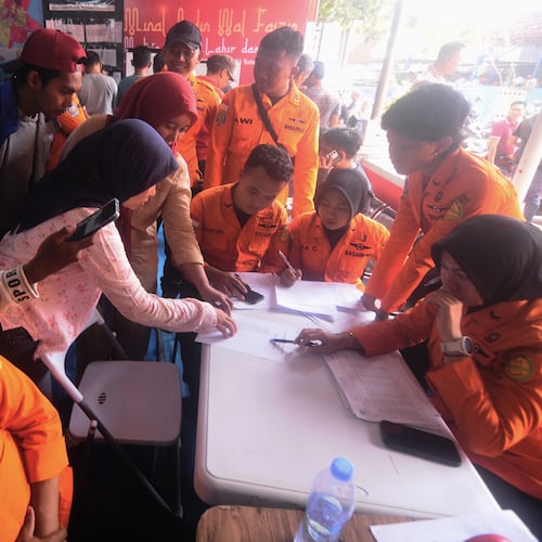 People look for the names of their family members on a passenger list after a ferry overturned in bad weather in the Java Sea, at the rescuers command center in Banjarmasin, South Kalimantan, Indonesia, Sunday, Sept. 13, 2026. (AP Photo/Iman Satria)